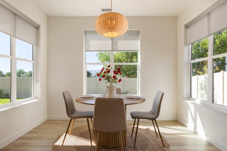 Dining room in a Copper Creek Parade of Home's wellness home featuring abundant natural light from surrounding windows and a modern pendant task light above the dining table